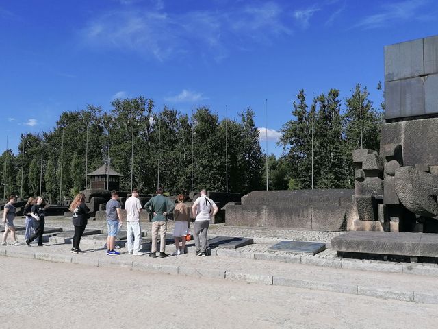 Junge Menschen im Gelände der Gedenkstätte vor einer massiven Steinkonstruktion, die nach einem Mahnmal aussieht.