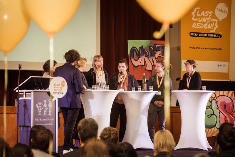 Ein Podium mit mehreren Stehtischen und Menschen.