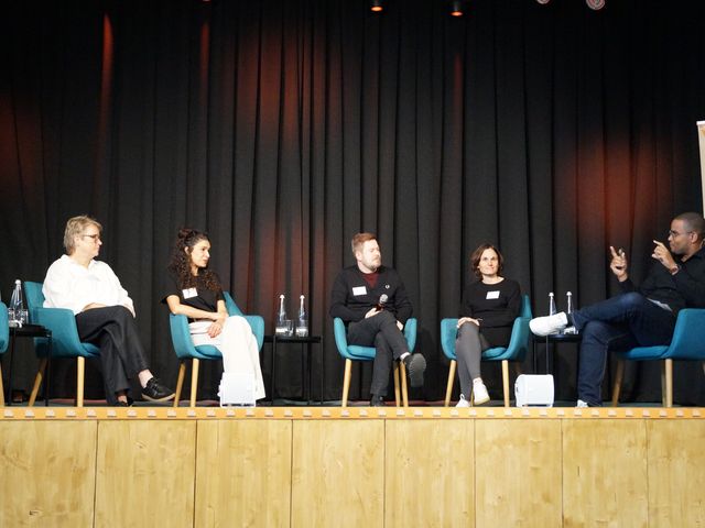 Fünf Personen sitzen während der Podiumsdiskussion auf der Bühne.