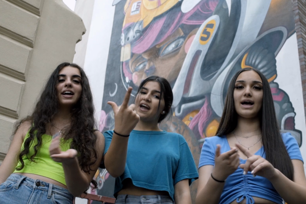 Drei junge Mädchen vor einer Graffiti-Wand.