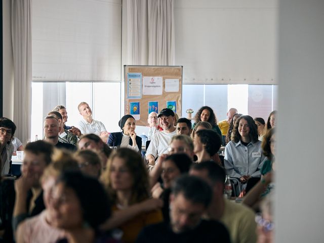 Eine große Gruppe in einem Plenum. Die Personen schauen nach vorn.
