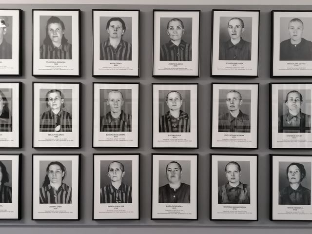 Eine Bildergalerie an einer Wand mit Schwarz-Weiß-Fotos und Namen ermordeter Menschen.