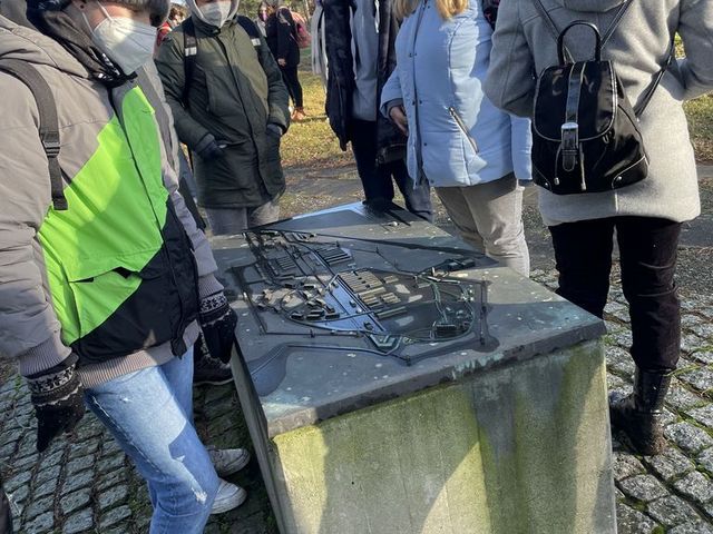 Mehrere junge Personen stehen vor einer Gedenkstätte.