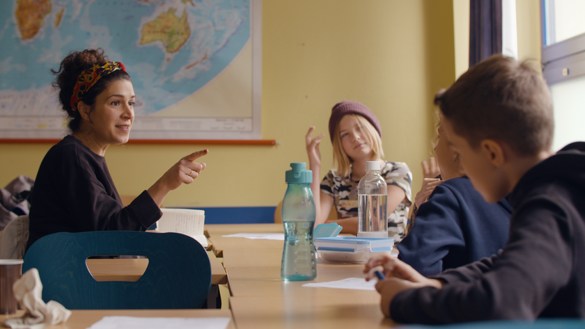 Drei an einem Tisch sitzende Personen.