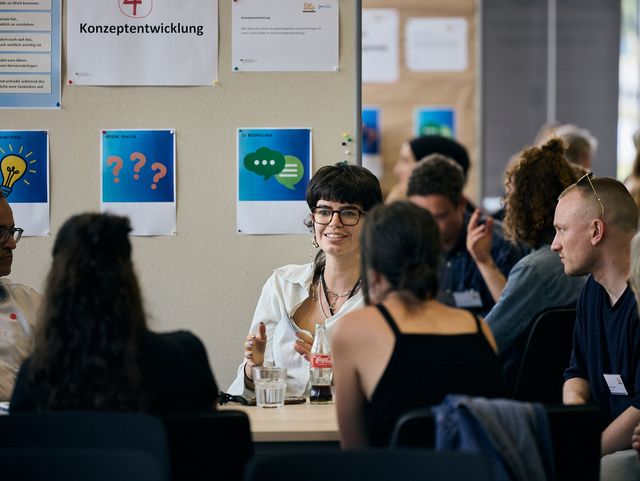 Eine Gruppe Menschen sitzt an einem Tisch und unterhält sich.