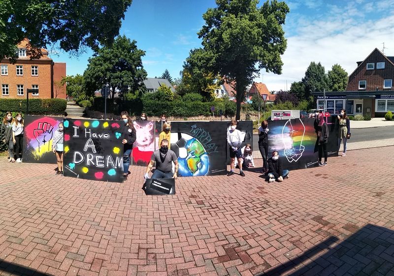Personen vor großen Tafeln mit Graffiti-Kunst.