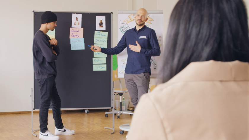 Zwei Personen stehen vor einem Flipchart.