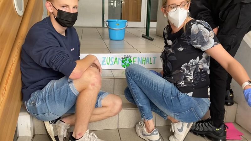 Menschen mit Maske auf einer Treppe.