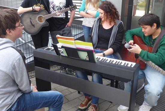 Eine Person spielt Keyboard und zwei Personen Gitarre.