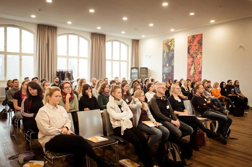 Mehrere Personen sitzen in einem Konferenzraum.