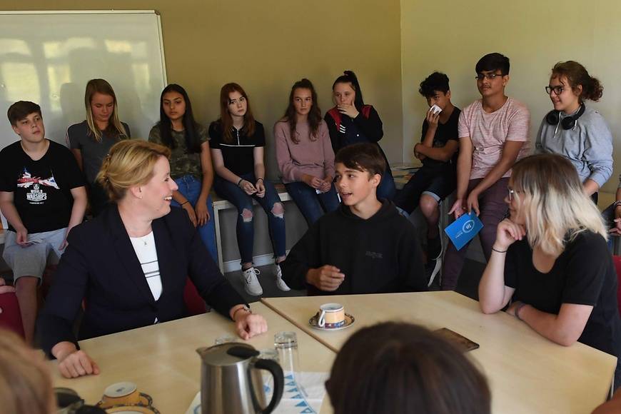 Bundesjugendministerin mit mehreren am Tisch stehenden Personen.