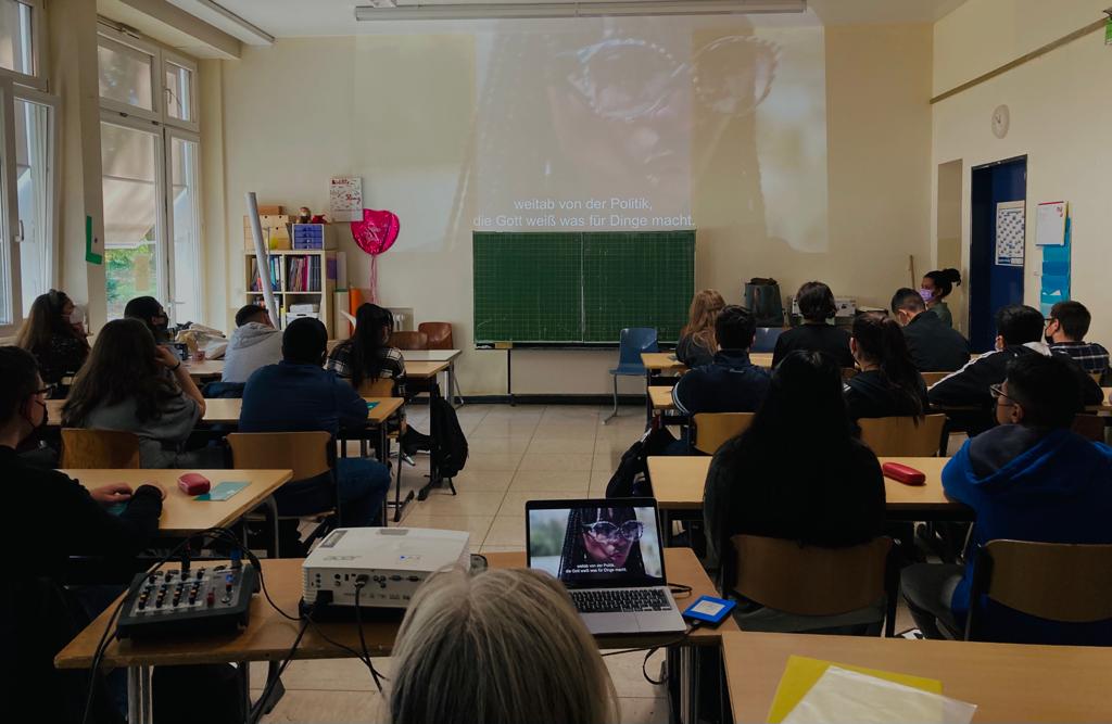 Schüler sitzen in einem Klassenraum und schauen einen an die Wand projizierten Film.