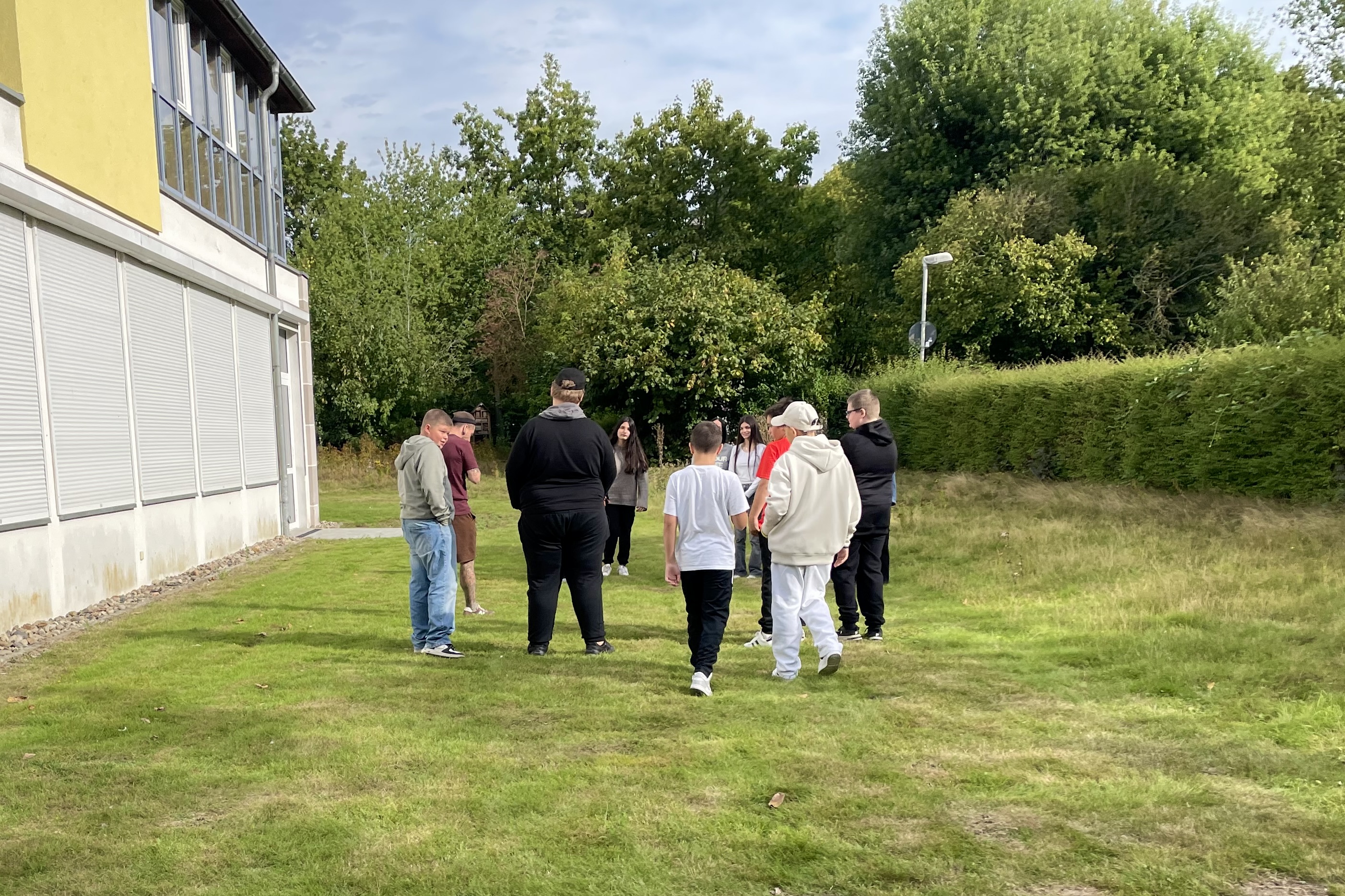 Eine Gruppe junger Menschen steht auf einer grünen Wiese.