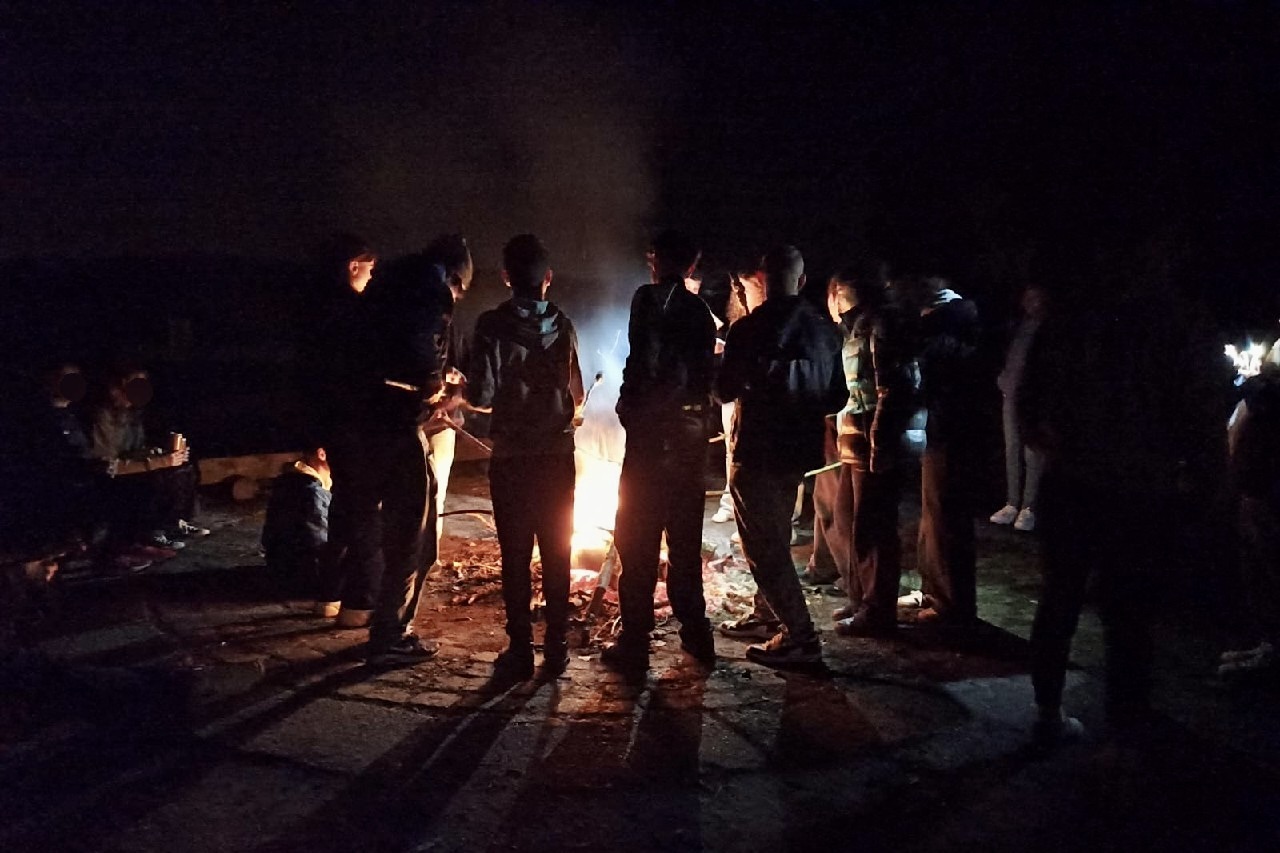 Eine Gruppe junger Menschen an einem Lagerfeuer.