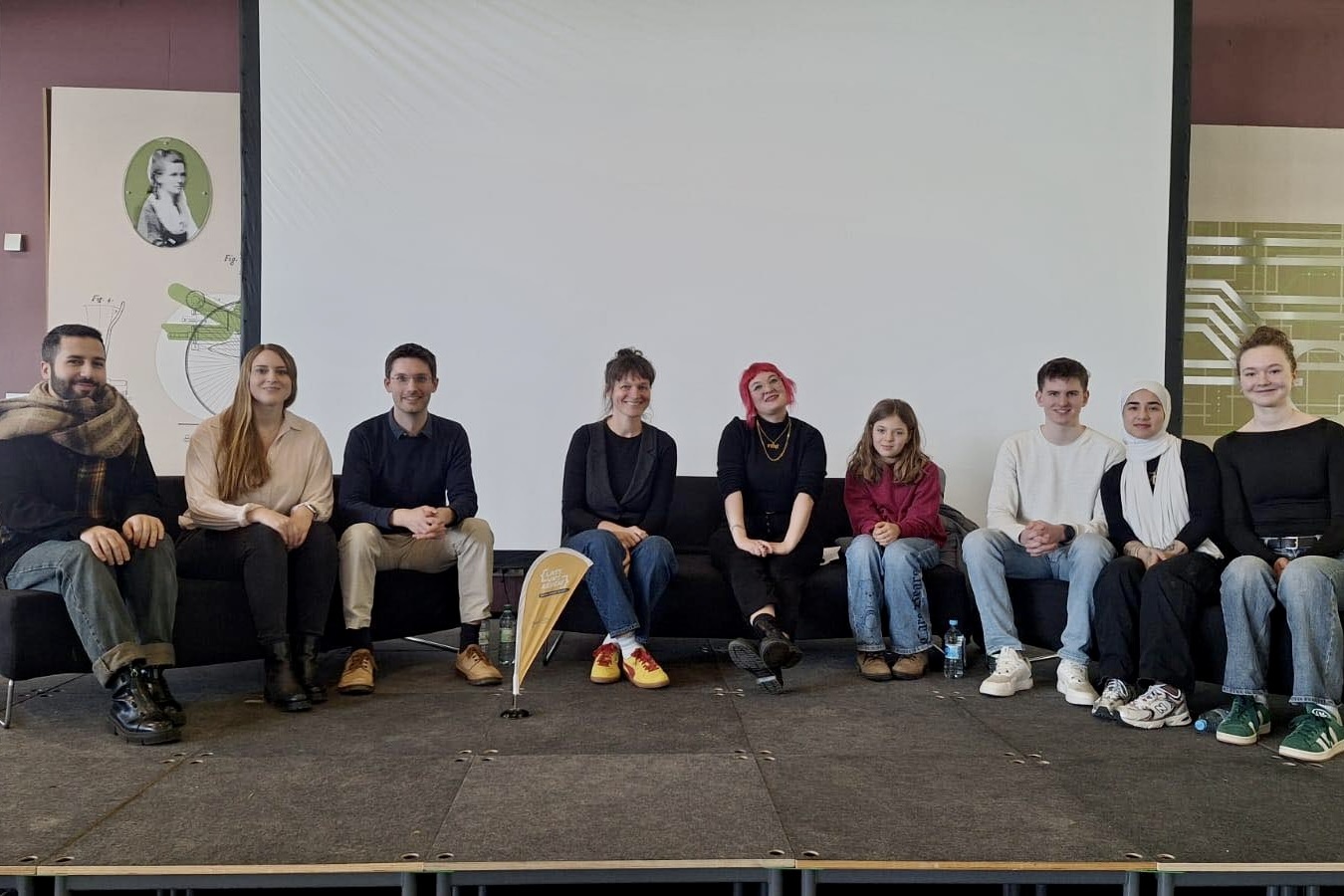 Eine Gruppe von Menschen sitzt auf Sofas aus einer Bühne.